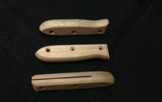 Three precision-shaped walnut knife handles, each featuring a slot for blade attachment and three cross-bored holes for secure fastening. Available in bulk for cutlery and tool manufacturing.